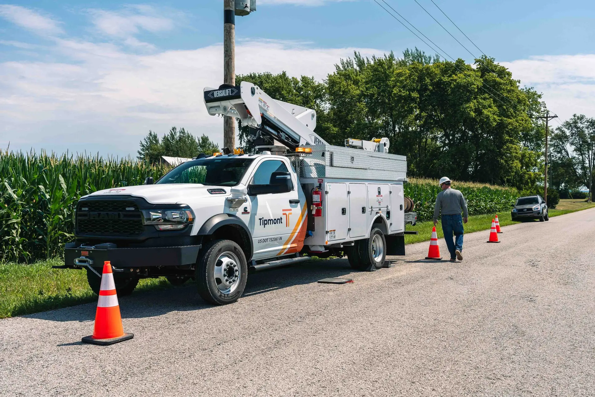 A Tipmont lineman placing cones around a bucket truck
